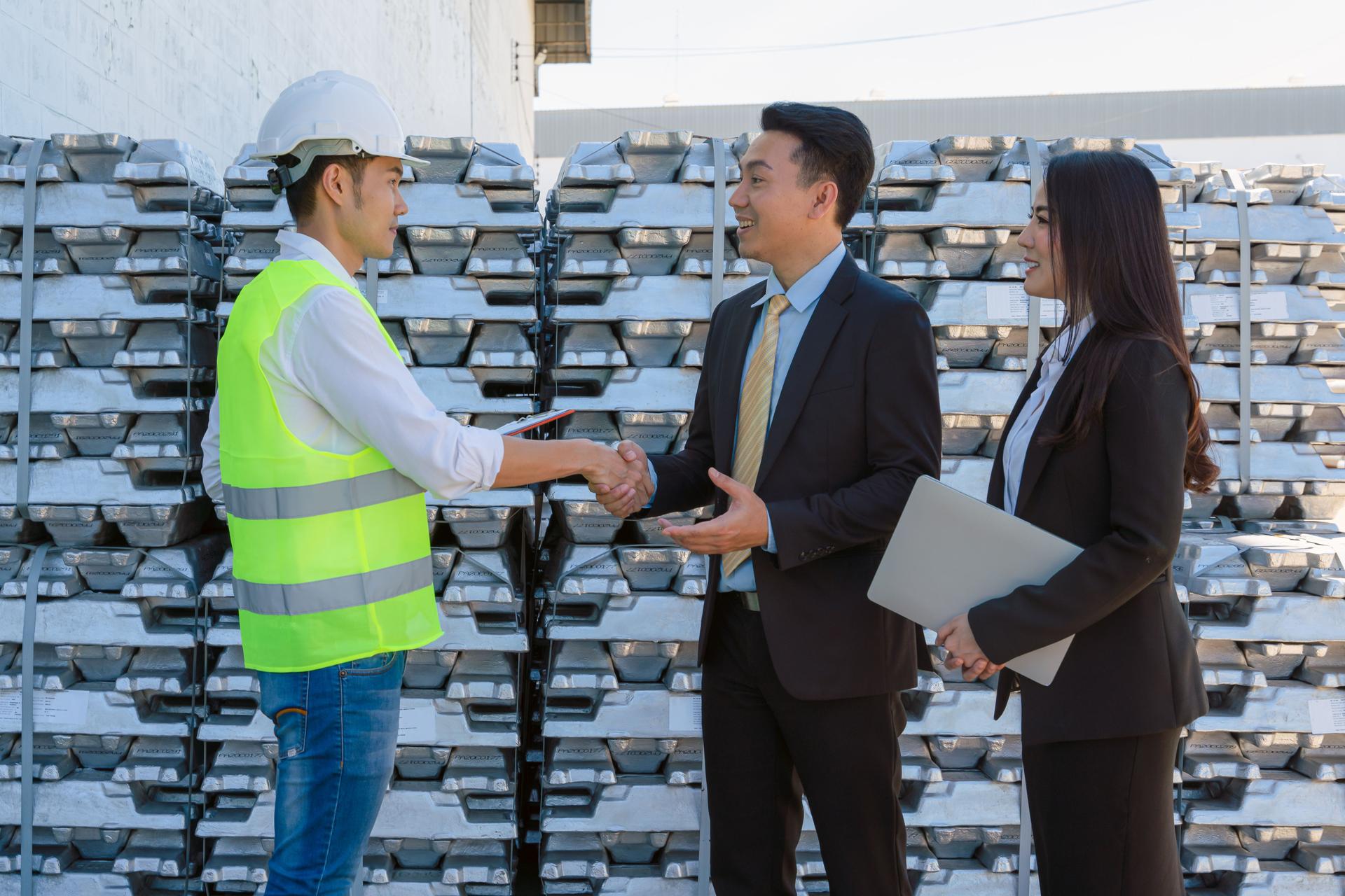 asian businessman having business discussion with executive engineeer at raw metal ingot storage warehouse for aluminum trading business