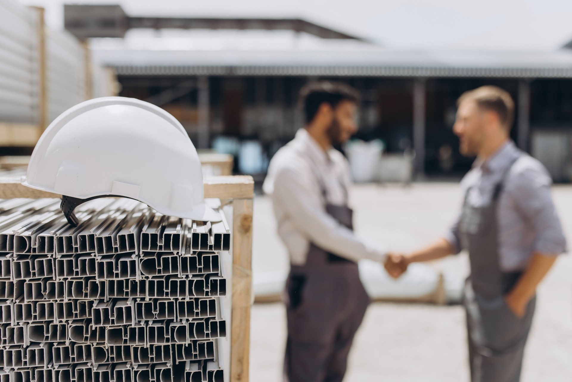 A manager and an employee shake hands next to a cargo for import or export. A white hard hat on the cargo on the background of two workers who signed the agreement.